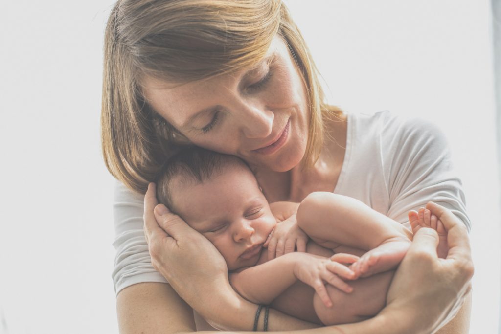 Photo of woman cradling a newborn on a white background