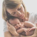 Photo of woman cradling a newborn on a white background